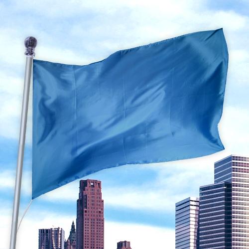 Blue flag waving on a pole against a city skyline, made of durable material in Solid Colored Flags - Premier Nylon.