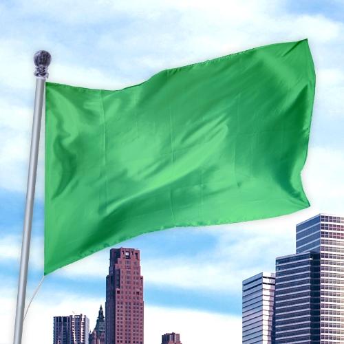 Green flag made from durable, lightweight material flying against a city skyline, Solid Colored Flags - Premier Nylon.