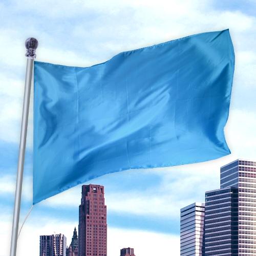 Bright blue flag made of durable nylon fabric flying on a pole against a city skyline, Solid Colored Flags - Premier Nylon.