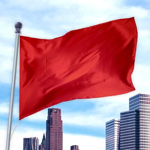 Red flag made of durable nylon fabric waving on a pole against a city skyline background, Solid Colored Flags - Premier Nylon