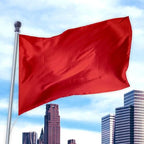 Red flag made of durable nylon fabric waving on a pole against a city skyline background, Solid Colored Flags - Premier Nylon