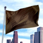 Solid Colored Flags - Premier Nylon in dark brown flying on a flagpole against a city skyline background during daytime.