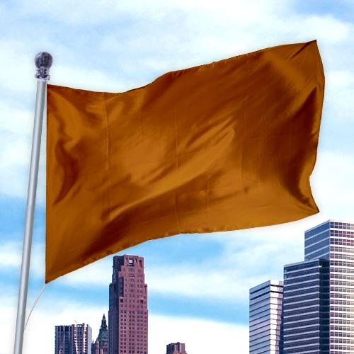 Solid Colored Flags - Premier Nylon orange flag waving on a pole against a city skyline and blue sky background