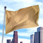 Gold-colored flag made of durable nylon material waving on a pole above a cityscape, Solid Colored Flags - Premier Nylon