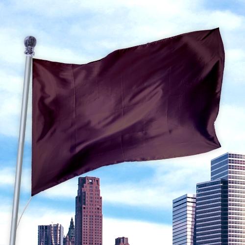 Solid Colored Flags - Premier Nylon flag in dark burgundy flying on a silver pole above city skyscrapers against a blue sky.
