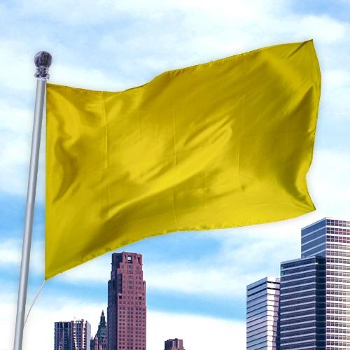 Yellow flag waving on a pole against a city skyline background, made from Solid Colored Flags - Premier Nylon material.