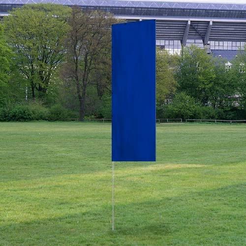 Solid Tall Advertising Flags in solid blue color standing upright on a grassy field with trees and a stadium in the background.