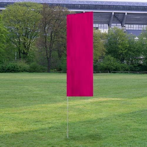 Solid Tall Advertising Flags with a vibrant magenta banner standing upright on a metal pole in a grassy outdoor area near trees and a stadium.