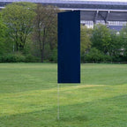 Solid Tall Advertising Flags standing on a grassy field with a background of trees and a large stadium structure.