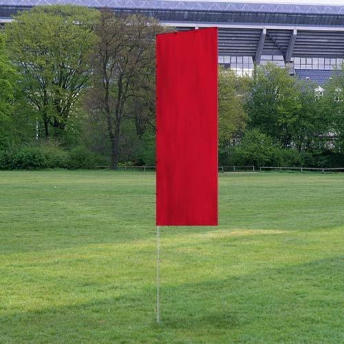 Solid Tall Advertising Flags in bright red standing upright on a grassy field with trees and a stadium structure in the background.
