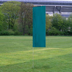 Solid Tall Advertising Flags in teal green standing upright on a grassy field with trees and a stadium in the background.