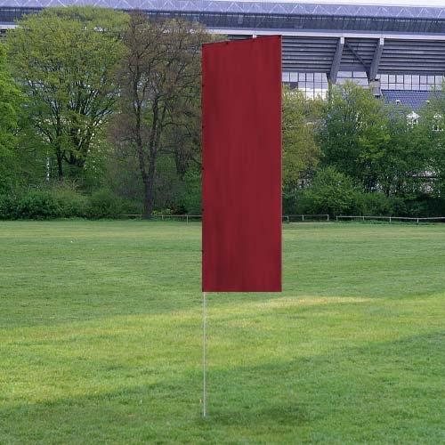 Solid Tall Advertising Flags in a deep red color standing upright on a grass field with trees and a stadium in the background.
