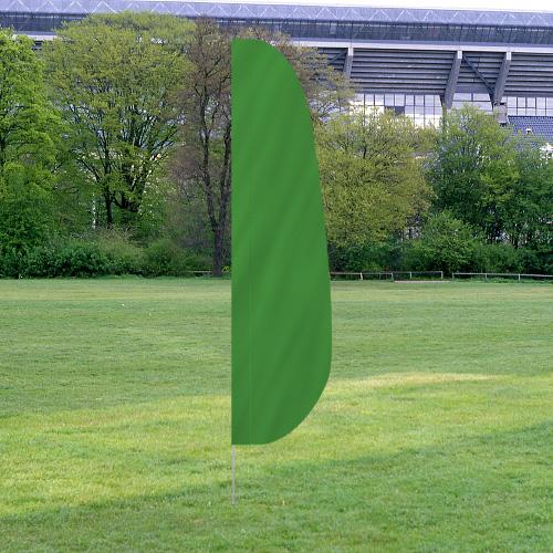 Solid Color Feather Flags in green standing on a grassy field with trees and a stadium in the background.
