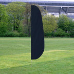 Solid Color Feather Flags in black standing upright on a grassy field with trees and a stadium in the background.