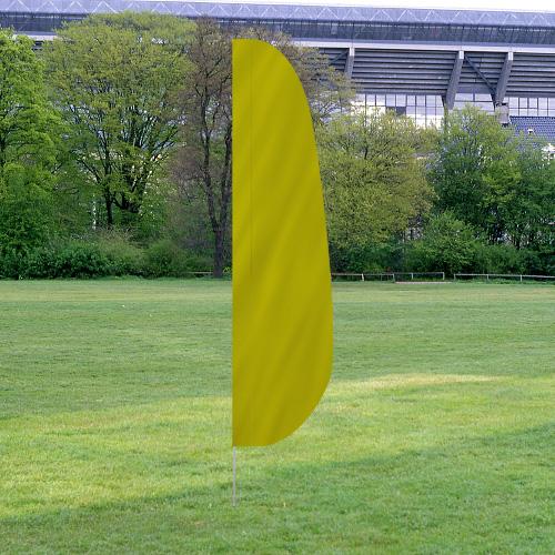 Bright yellow Solid Color Feather Flags standing on a grassy field with trees and a stadium structure in the background