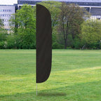 Solid Color Flutter Flags in black standing upright on a grassy field with trees and buildings in the background