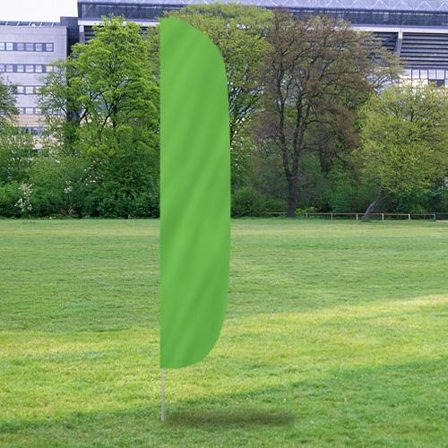 Solid Color Flutter Flags in a vibrant green shade standing upright on a grassy field with trees and buildings in the background.