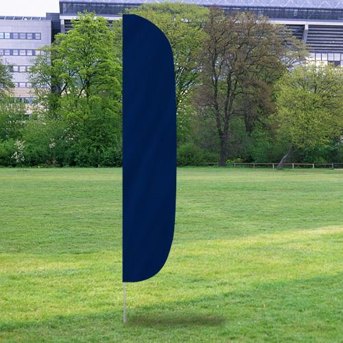 Solid Color Flutter Flags in a solid dark blue color standing upright on a grassy field with trees and a building in the background.