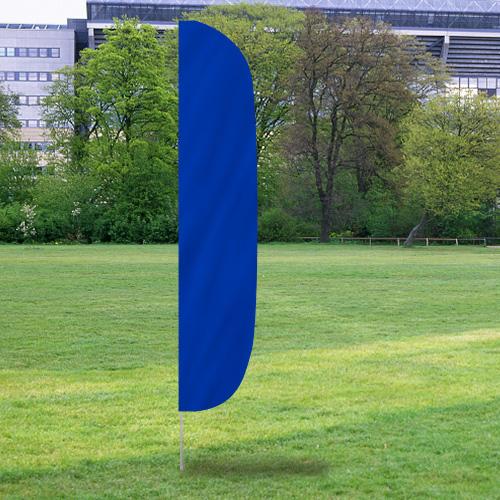Solid Color Flutter Flags in vibrant blue displaying prominently outdoors on a grassy area with trees and buildings in the background