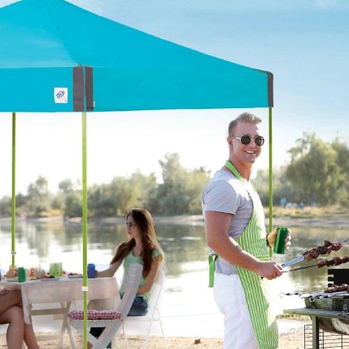 man grilling under blue tent