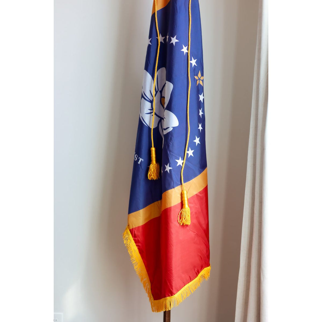 Indoor Mississippi state flag with gold fringe and tassel cords on pole