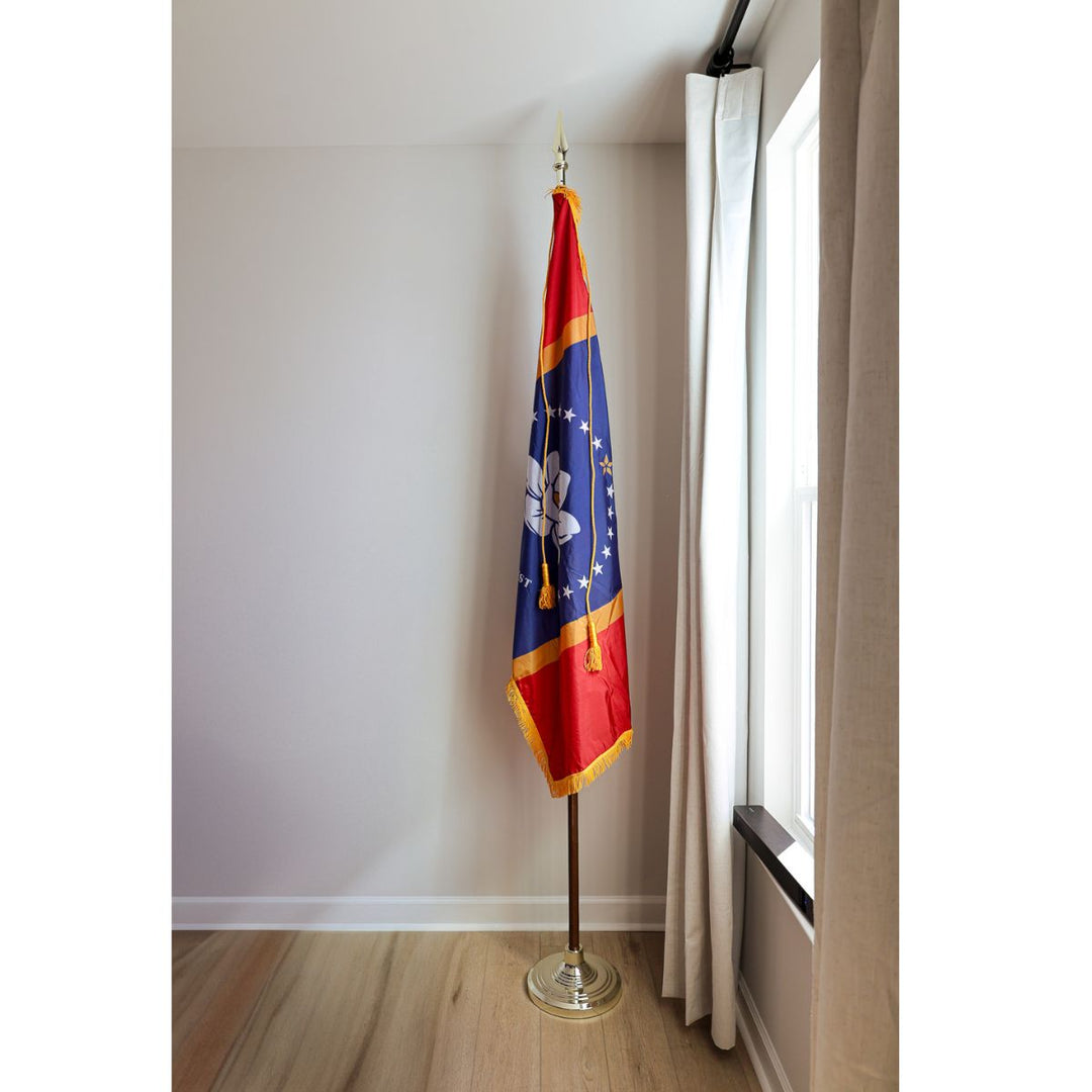 Indoor Mississippi state flag display with pole, gold fringe, tassels, and floor stand